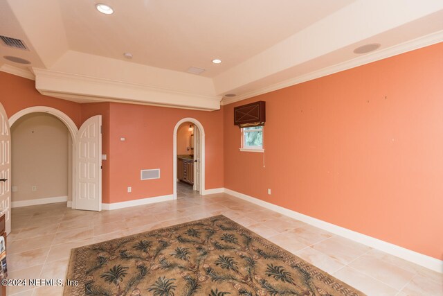 unfurnished room featuring arched walkways, a tray ceiling, and visible vents