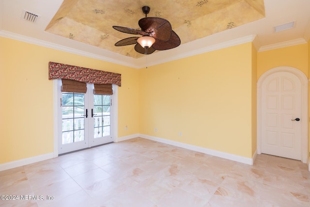 empty room with ornamental molding, a tray ceiling, visible vents, and baseboards