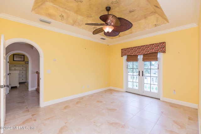 empty room with baseboards, a tray ceiling, french doors, and ornamental molding