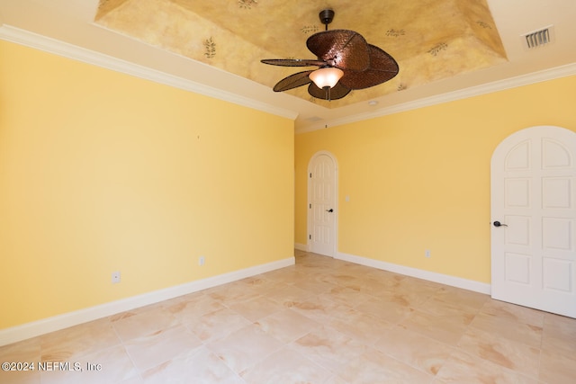 spare room featuring baseboards, a tray ceiling, visible vents, and crown molding