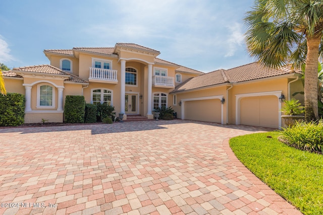 mediterranean / spanish-style home featuring french doors, a balcony, an attached garage, and stucco siding