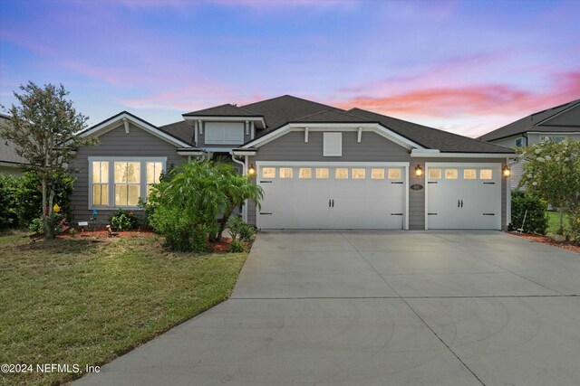 view of front of home with a garage and a lawn