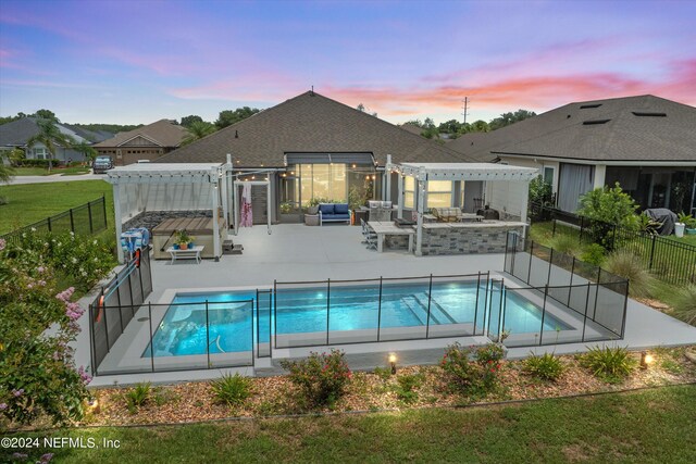 pool at dusk with a pergola, a patio, and an outdoor living space