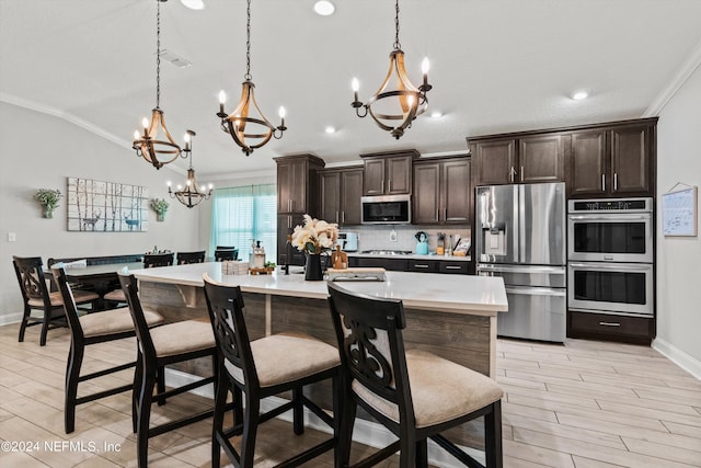 kitchen featuring a kitchen island with sink, decorative light fixtures, a breakfast bar area, and appliances with stainless steel finishes