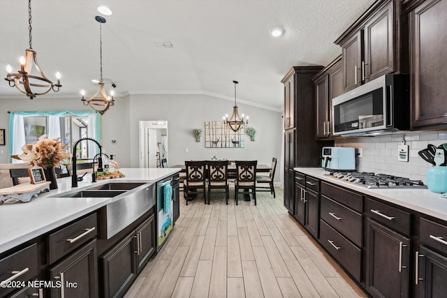 kitchen with lofted ceiling, sink, appliances with stainless steel finishes, a notable chandelier, and decorative light fixtures