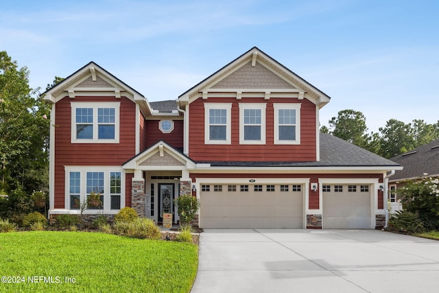 craftsman house featuring a garage and a front lawn