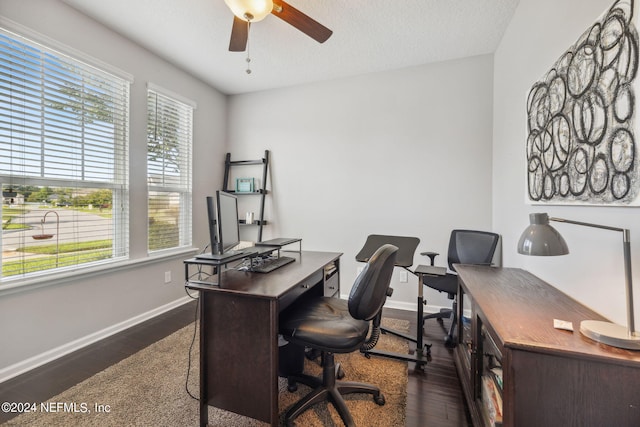 home office featuring dark wood-type flooring, ceiling fan, and a healthy amount of sunlight