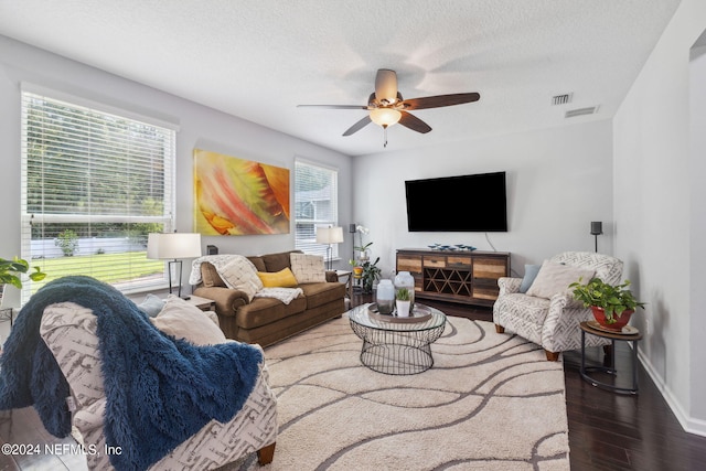 living room with ceiling fan, dark wood-type flooring, and a textured ceiling