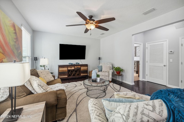 living room featuring dark hardwood / wood-style flooring, a textured ceiling, and ceiling fan