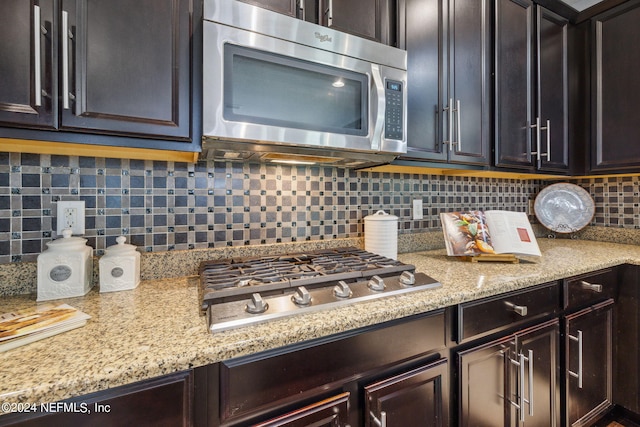 kitchen featuring stainless steel appliances, dark brown cabinets, and backsplash