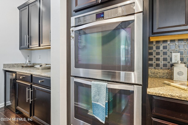 kitchen with wine cooler, backsplash, light stone countertops, and stainless steel double oven