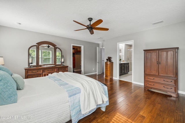 bedroom featuring dark wood-type flooring, a walk in closet, ensuite bath, a closet, and ceiling fan