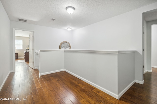 hallway featuring dark wood-type flooring and a textured ceiling