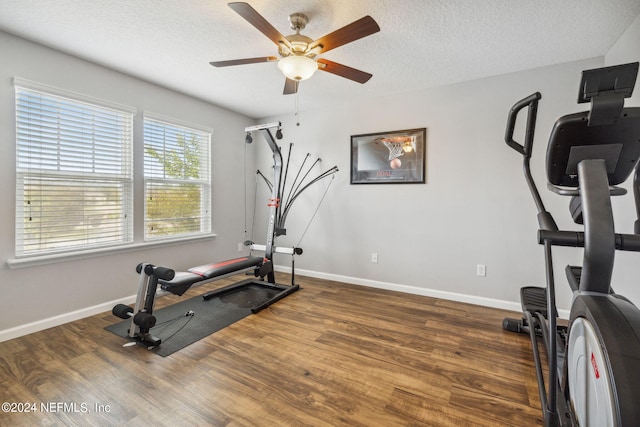 workout area featuring ceiling fan, dark wood-type flooring, and a textured ceiling