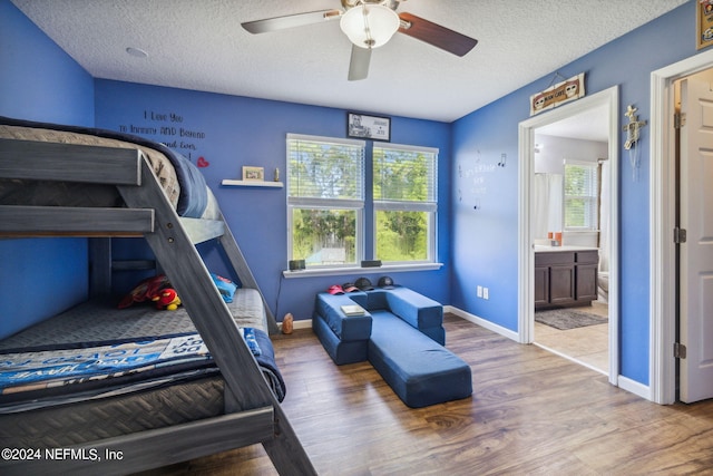 bedroom featuring hardwood / wood-style flooring, a textured ceiling, ceiling fan, and ensuite bathroom