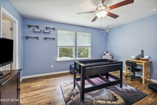 playroom featuring ceiling fan, hardwood / wood-style floors, and a textured ceiling