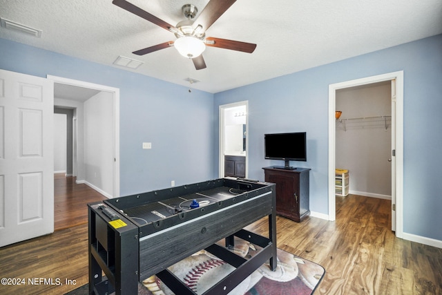 recreation room with ceiling fan, dark hardwood / wood-style flooring, and a textured ceiling