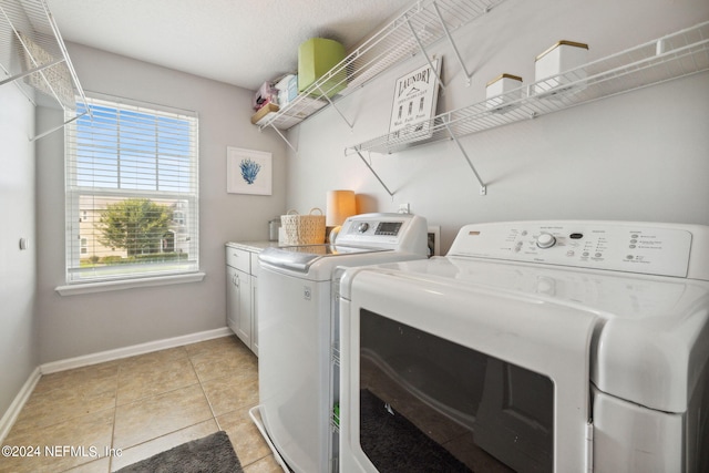 washroom featuring separate washer and dryer, light tile patterned floors, and cabinets