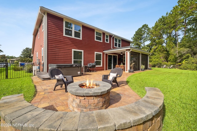 rear view of house featuring a patio area, a hot tub, a lawn, an outdoor fire pit, and a sunroom