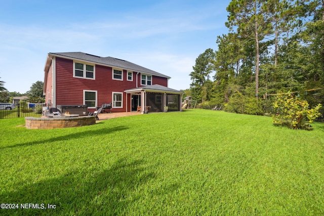 back of house featuring a lawn, a hot tub, a sunroom, and a patio area