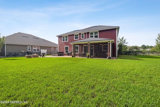 back of property with a lawn, a sunroom, a patio, and a hot tub