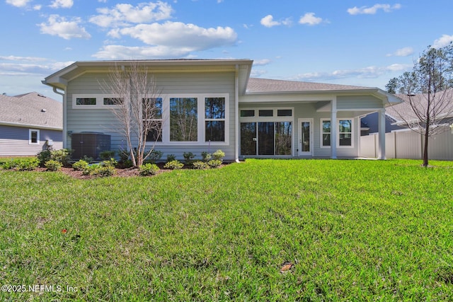 rear view of property with a lawn and fence