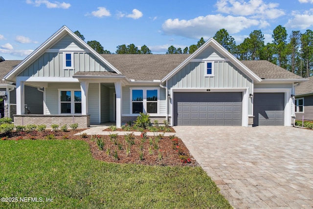 view of front of home with a front lawn, decorative driveway, board and batten siding, and an attached garage