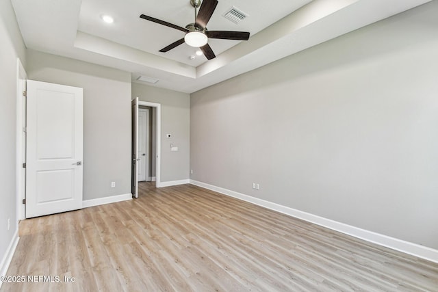 unfurnished bedroom with light wood-type flooring, visible vents, a raised ceiling, recessed lighting, and baseboards