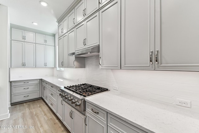 kitchen with decorative backsplash, gas cooktop, light wood finished floors, and under cabinet range hood