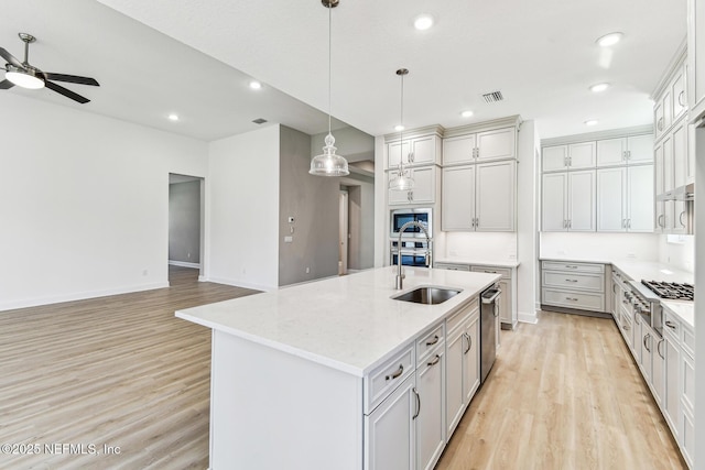 kitchen featuring light wood finished floors, visible vents, a ceiling fan, and a sink