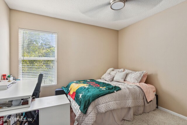 bedroom with a textured ceiling, multiple windows, carpet flooring, and ceiling fan