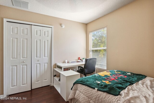 bedroom featuring a closet, a textured ceiling, and dark wood-type flooring