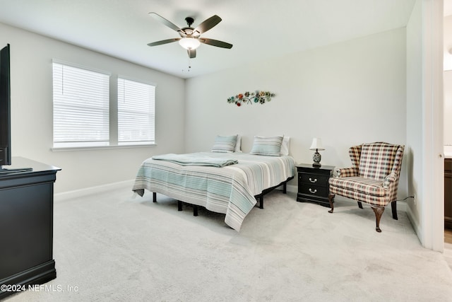 bedroom featuring light colored carpet, ceiling fan, and ensuite bath