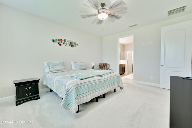 bedroom featuring ceiling fan, light colored carpet, and ensuite bath