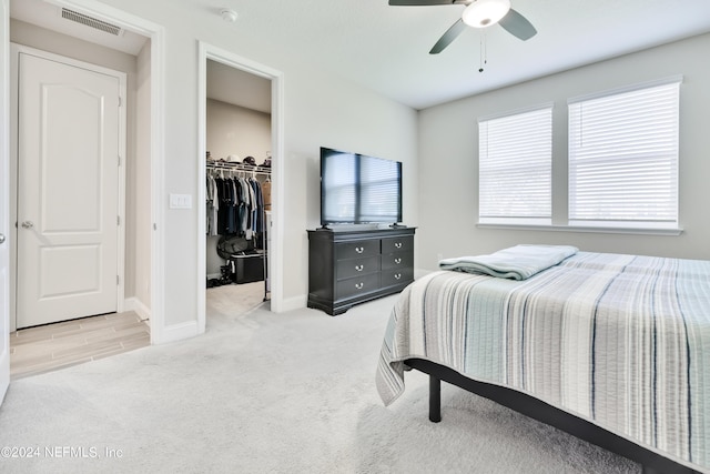 bedroom featuring ceiling fan, a spacious closet, light colored carpet, and a closet