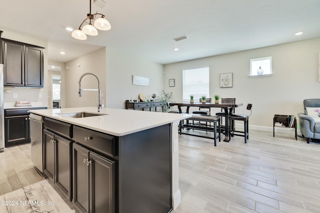 kitchen featuring decorative light fixtures, dishwasher, sink, white refrigerator, and a kitchen island with sink