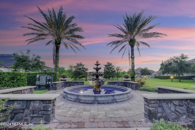 patio terrace at dusk featuring a yard