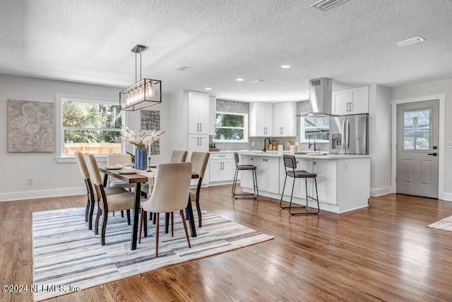 dining space with hardwood / wood-style flooring, an inviting chandelier, a textured ceiling, and sink