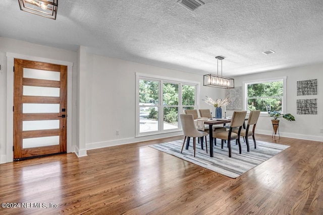 dining room with a wealth of natural light, dark hardwood / wood-style floors, and an inviting chandelier