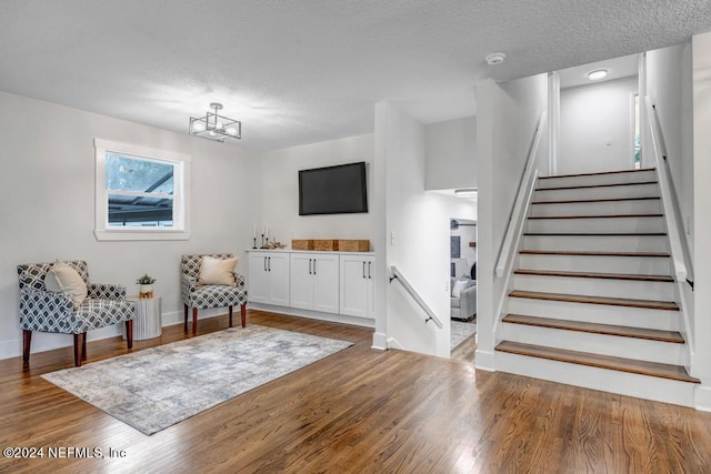 foyer entrance featuring hardwood / wood-style floors, a notable chandelier, and a textured ceiling