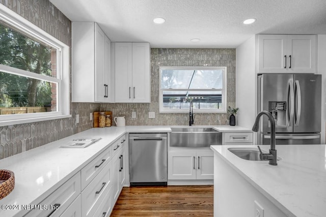 kitchen with wood-type flooring, stainless steel appliances, white cabinetry, and sink