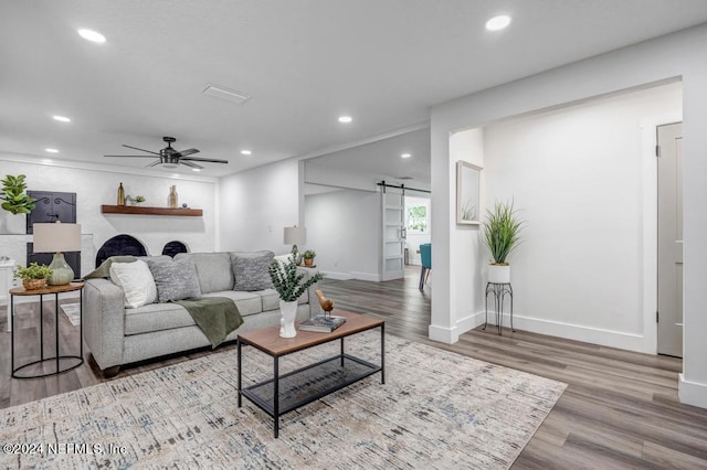 living room featuring a barn door, ceiling fan, and hardwood / wood-style flooring