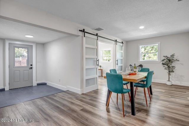 dining space with a textured ceiling, a barn door, and wood-type flooring