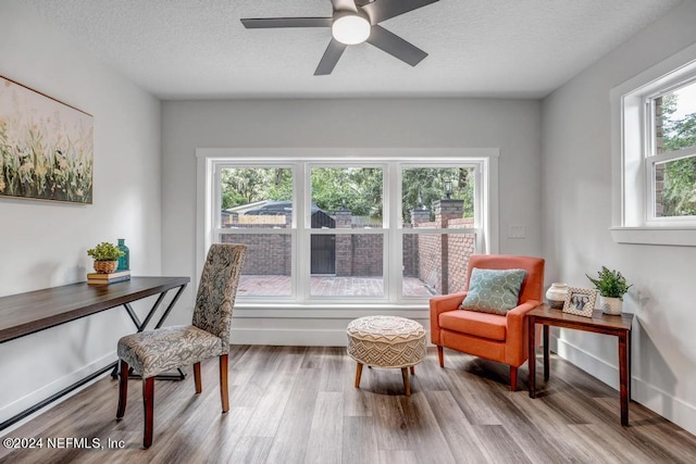 living area with a textured ceiling, plenty of natural light, ceiling fan, and wood-type flooring