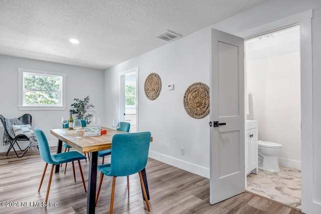 dining space with plenty of natural light, light hardwood / wood-style floors, and a textured ceiling