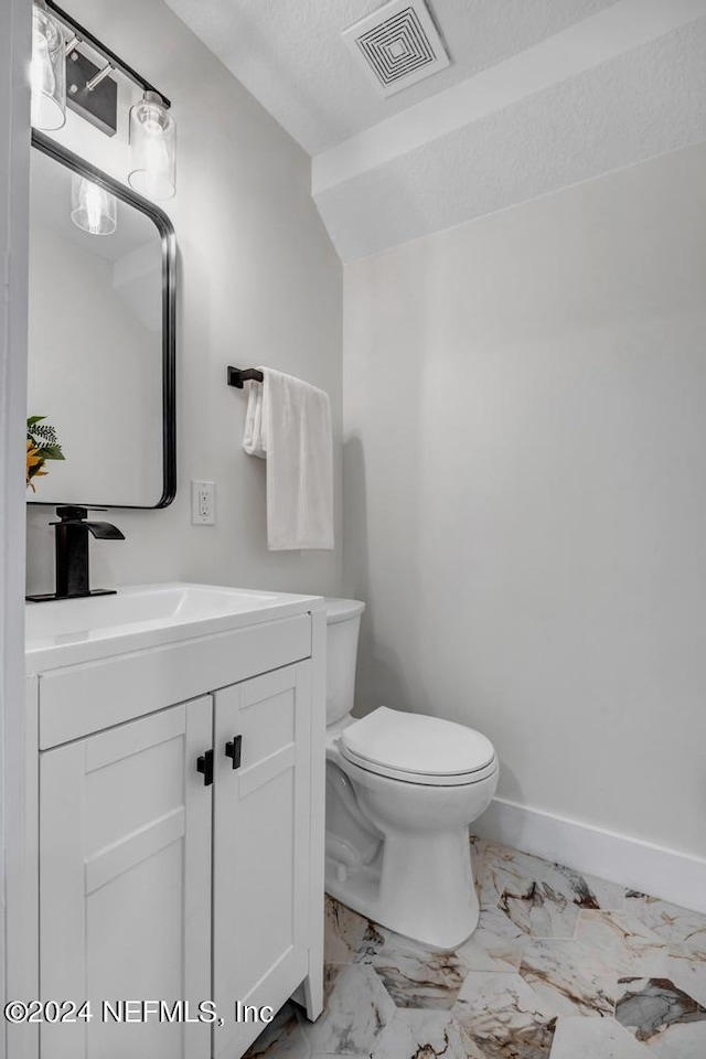 bathroom with tile patterned flooring, toilet, a textured ceiling, and vanity