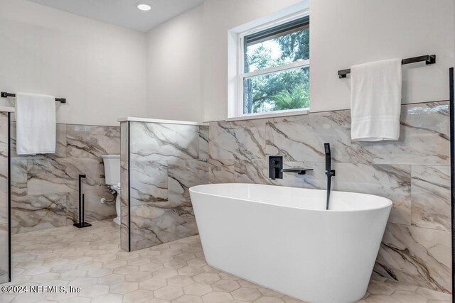 bathroom with tile walls, separate shower and tub, and tile patterned flooring