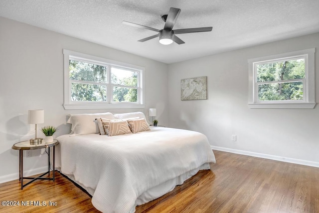 bedroom featuring a textured ceiling, wood-type flooring, and ceiling fan