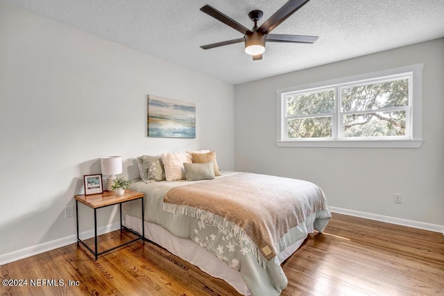 bedroom featuring a textured ceiling, ceiling fan, and wood-type flooring