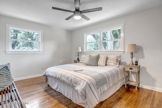 bedroom with multiple windows, a textured ceiling, hardwood / wood-style floors, and ceiling fan